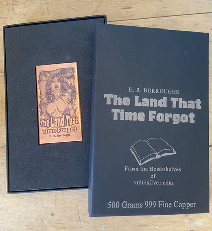 A square dark gray presentation box set on a light wood surface, showing the front cover of 'The Land That Time Forgot' by E. R.